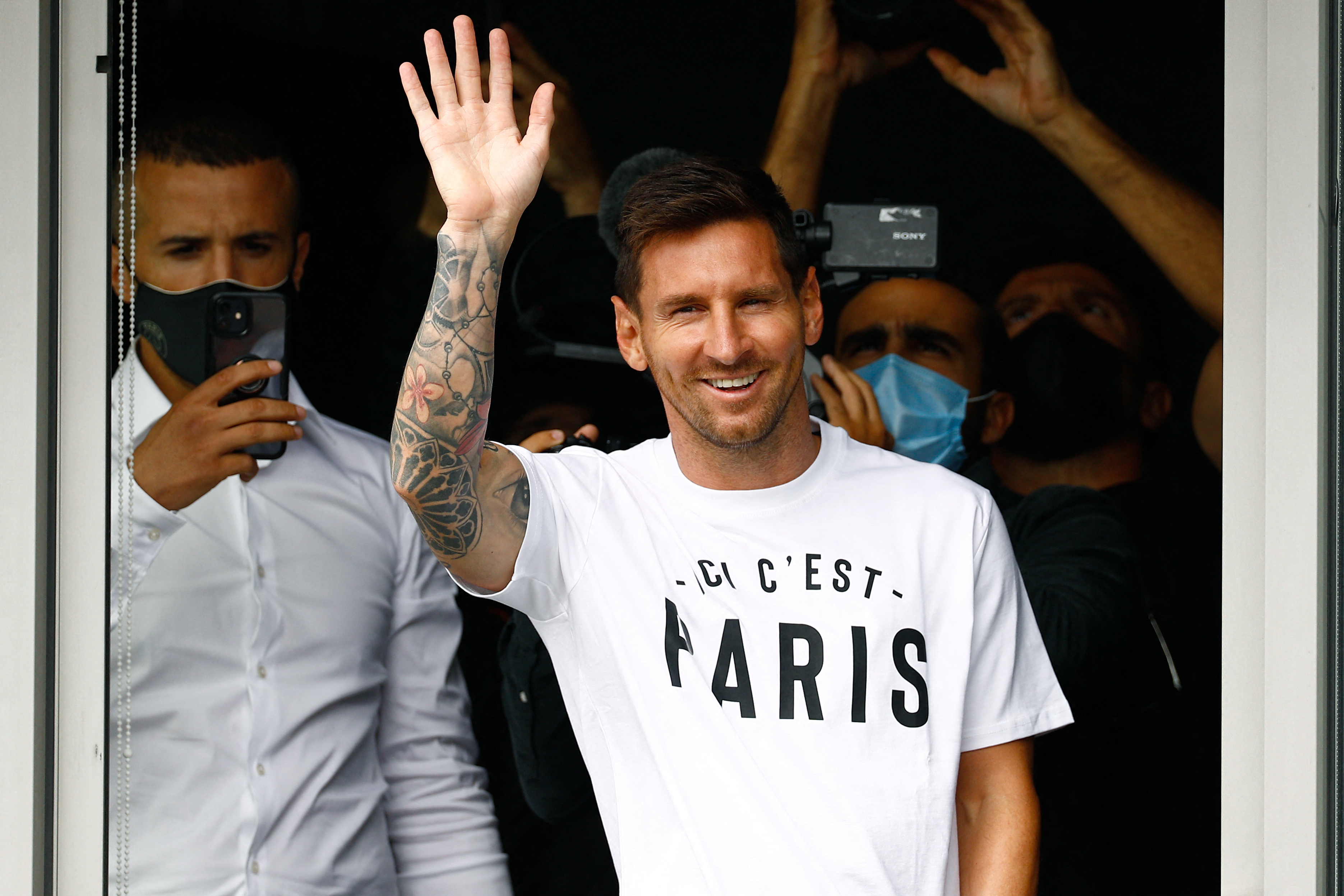 Lionel Messi saluda a los aficionados del PSG que llegaron al aeropuerto Le Bourget. En las próximas horas firmará el contrato por dos temporadas con el club parisino. Foto Prensa Libre: AFP.