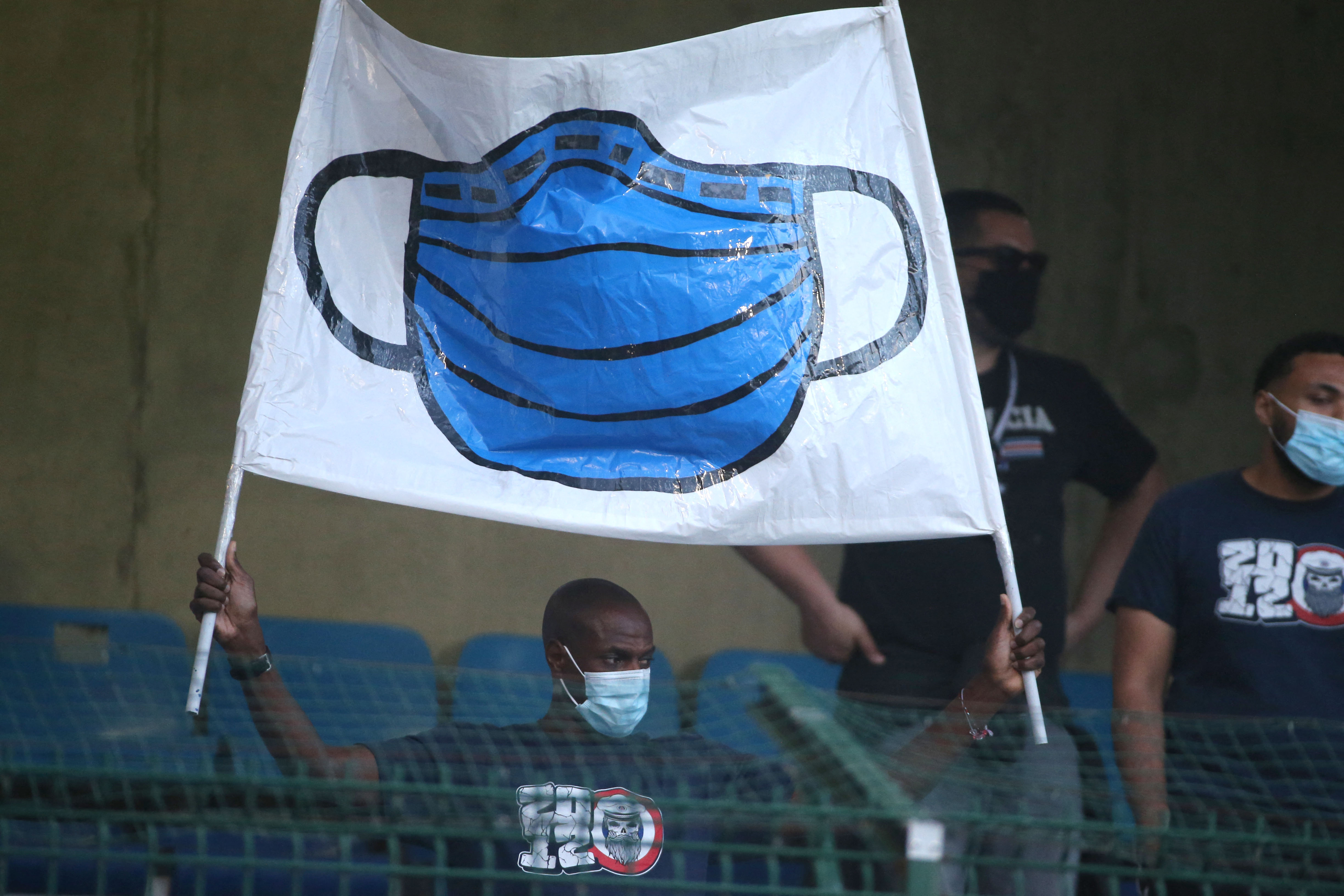 A fan holds up a banner showing a protective face mask worn to help stop the spread of Covid-19, prior to the start of the French L1 football match between Paris Saint-Germain (PSG) and ES Troyes at the Stade de l'Aube in Troyes on August 7, 2021. (Photo by François NASCIMBENI / AFP)
