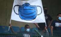 A fan holds up a banner showing a protective face mask worn to help stop the spread of Covid-19,  prior to the start of the French L1 football match between Paris Saint-Germain (PSG) and ES Troyes at the Stade de l'Aube in Troyes on August 7, 2021. (Photo by François NASCIMBENI / AFP)
