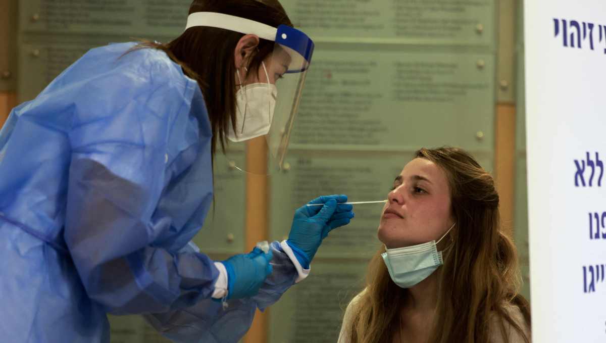 A paramedic with Israel's Magen David Adom medical service performs a rapid COVID-19 antigenic test in Jerusalem on August 8, 2021. - Israel set up rapid coronavirus testing stations across the country on Sunday, the Magen David Adom emergency service said, as the government tries to stave off another pandemic lockdown. (Photo by MENAHEM KAHANA / AFP)
