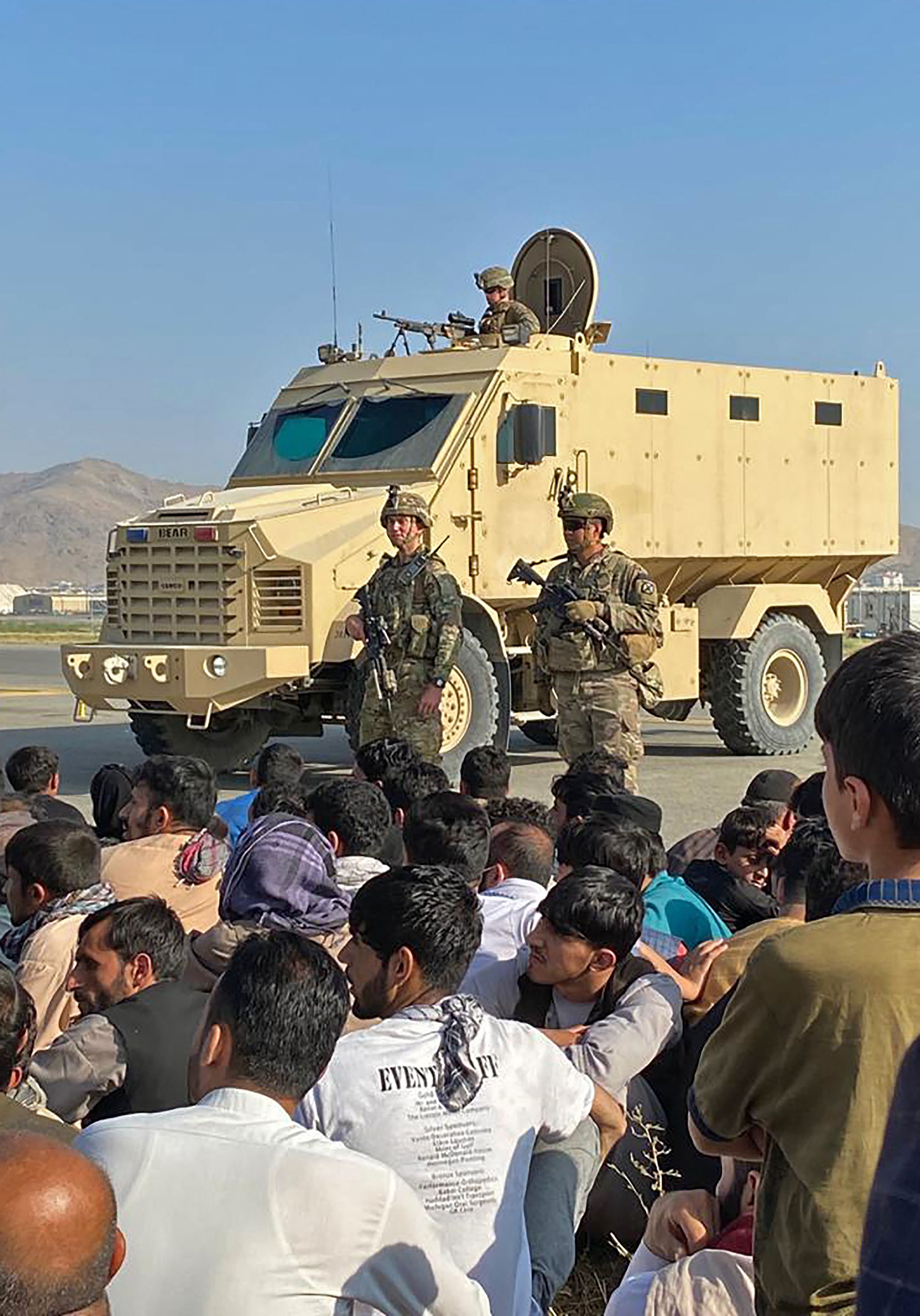 Los afganos se agolpan en el aeropuerto mientras los soldados estadounidenses montan guardia en Kabul el 16 de agosto de 2021. Foto Prensa Libre: AFP.