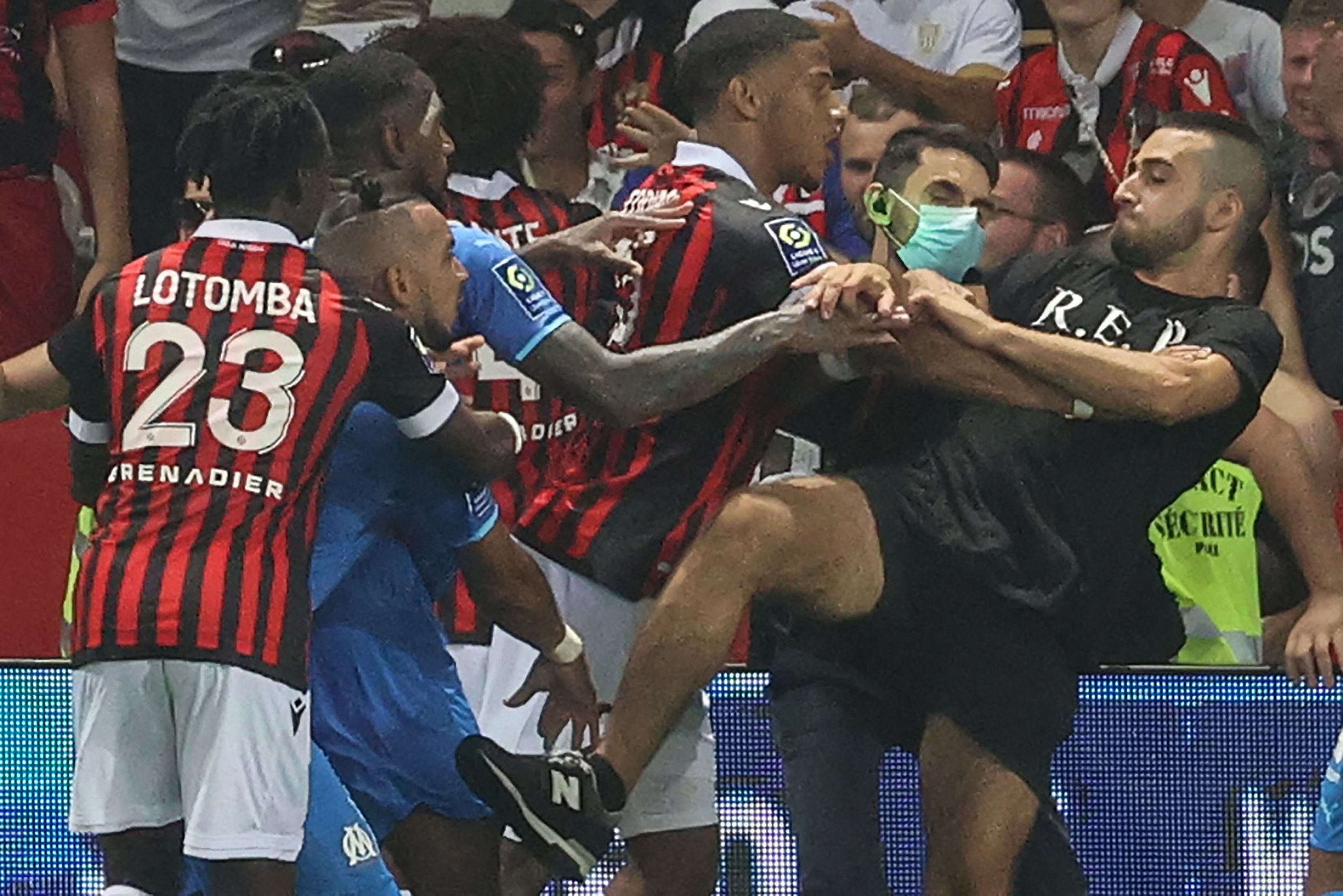 El mediocentro Dimitri Payet (2do Izq) reacciona con los jugadores del OGC Niza (rojo y negro) y del Olympique de Marsella (azul) a un fan que invadió la cancha. (Foto Prensa Libre: AFP)