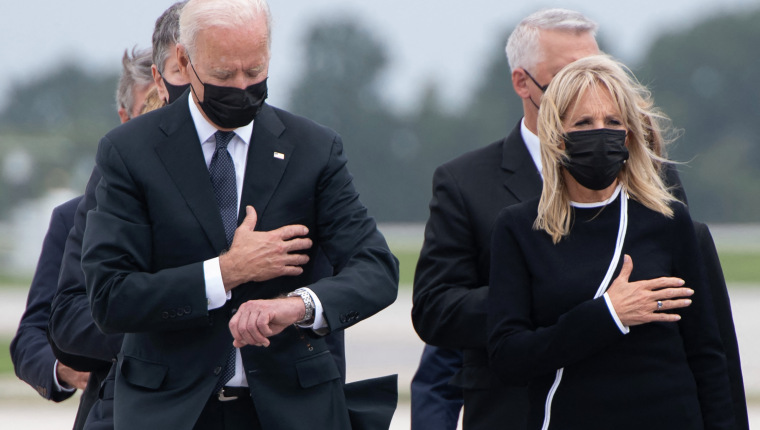 US President Joe Biden looks down alongside First Lady Jill Biden as they attend the dignified transfer of the remains of a fallen service member at Dover Air Force Base in Dover, Delaware, August, 29, 2021, one of the 13 members of the US military killed in Afghanistan last week. - President Joe Biden prepared Sunday at a US military base to receive the remains of the 13 American service members killed in an attack in Kabul, a solemn ritual that comes amid fierce criticism of his handling of the Afghanistan crisis. Biden and his wife, Jill, both wearing black and with black face masks, first met far from the cameras with relatives of the dead in a special family center at Dover Air Force Base in Delaware.The base, on the US East Coast about two hours from Washington, is synonymous with the painful return of service members who have fallen in combat. (Photo by SAUL LOEB / AFP)