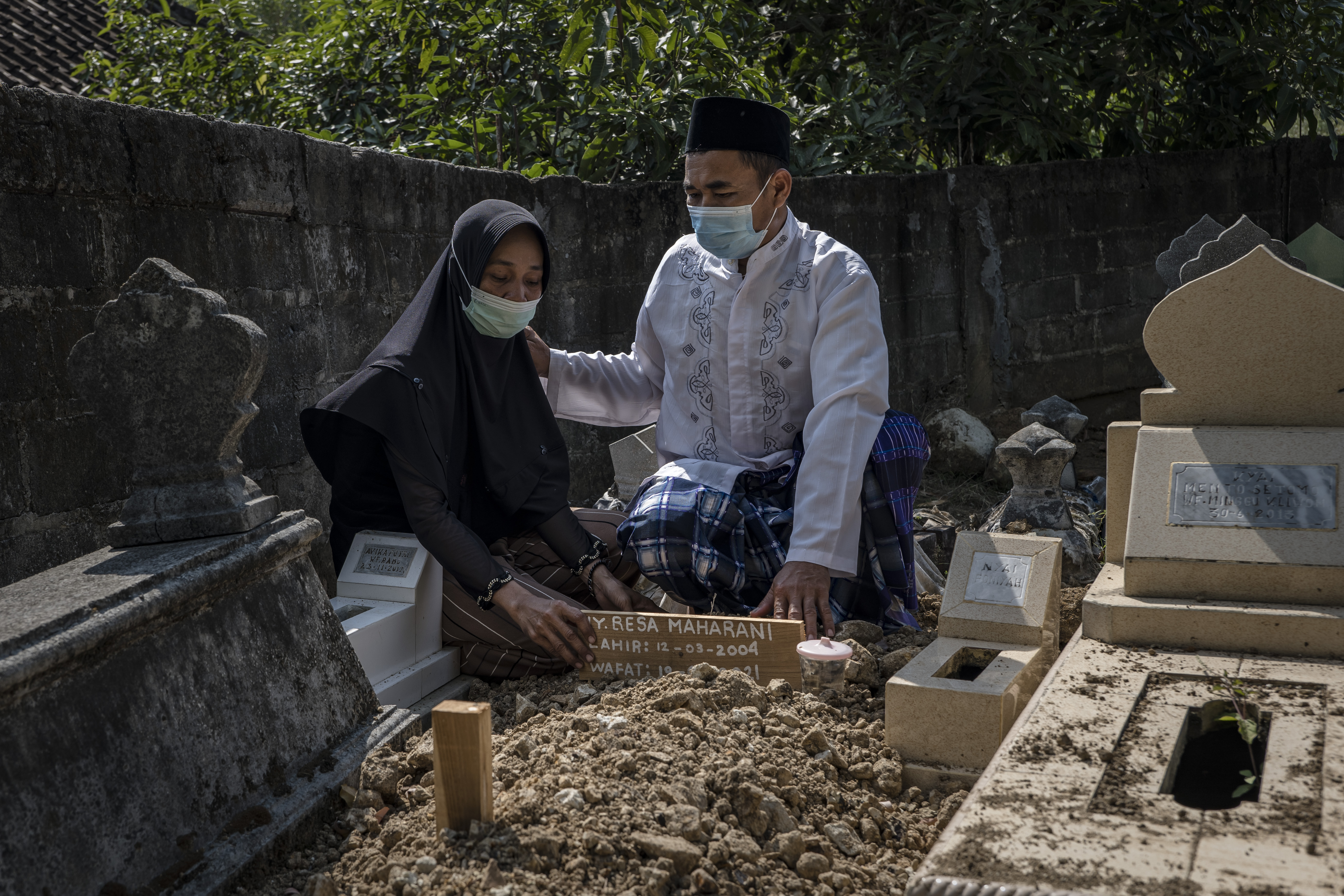 Paiman, a la izquierda, y Martinah sostienen un retrato de su hija, Raesa Maharani, que murió de COVID-19 a los 17 años, en su casa de Yogyakarta, Indonesia, el 29 de julio de 2021. (Foto Prensa Libre: Ulet Ifansasti/The New York Times)