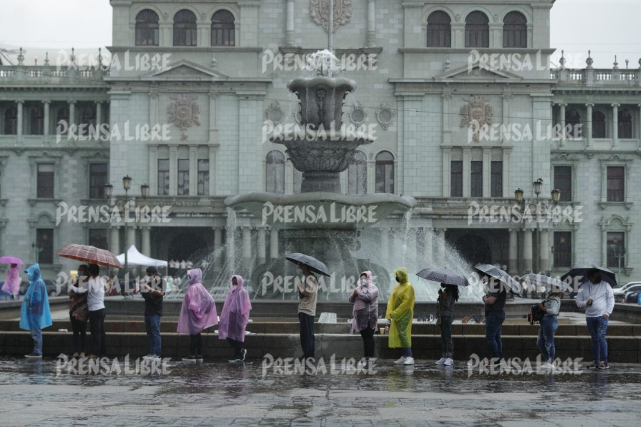 Decenas de guatemaltecos esperan bajo la lluvia para ser vacunados en el puesto habilitado en la Plaza de la Constitución. Fotografía: Prensa Libre (Esbin García). 