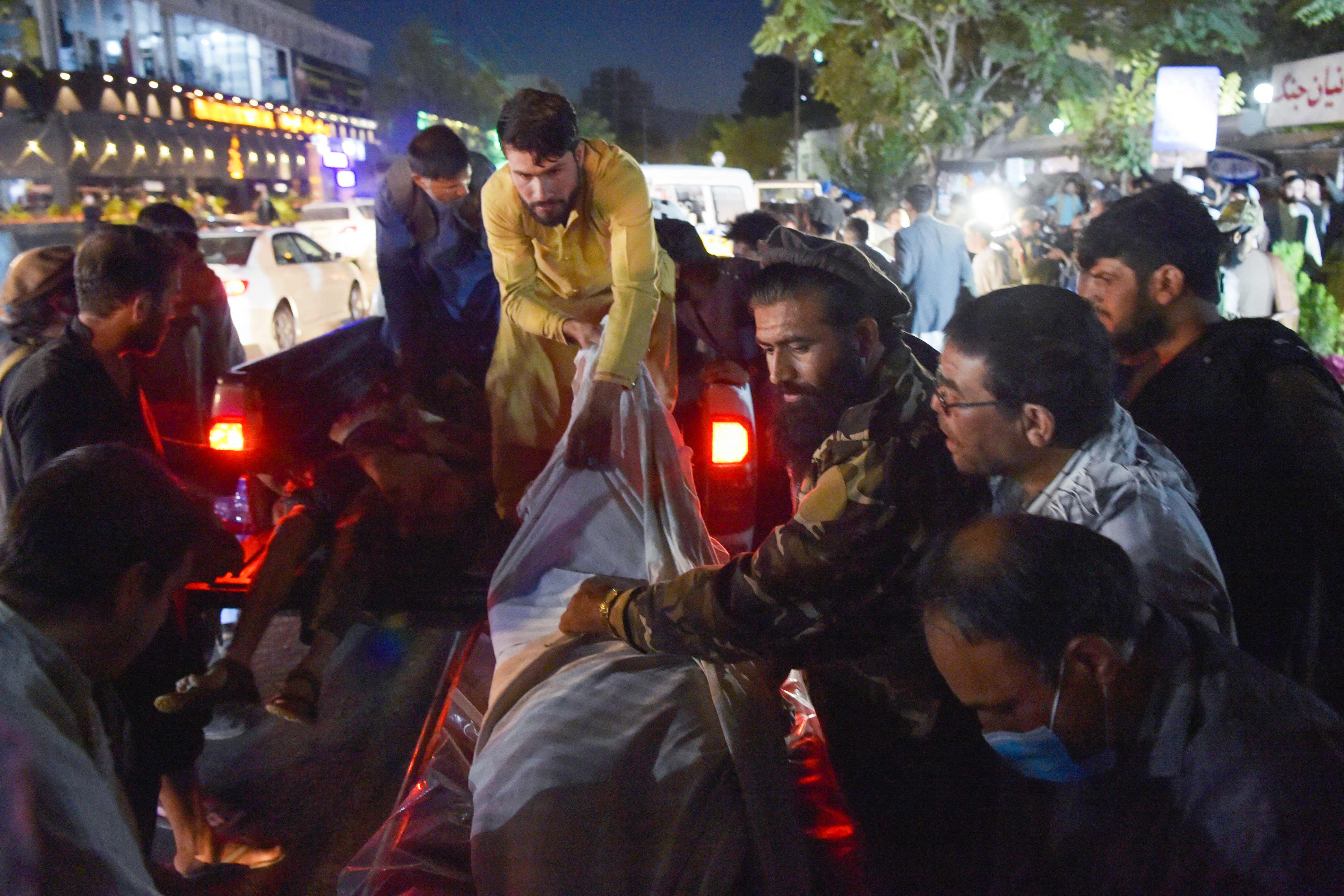 Voluntarios y personal médico descargan cadáveres de una camioneta fuera de un hospital después de dos poderosas explosiones fuera del aeropuerto de Kabul. (Foto Prensa Libre: AFP)
