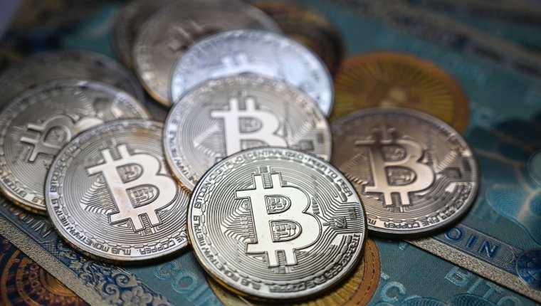 La fotografía ilustrativa tomada el 19 de julio de 2021 en Estambul muestra un billete físico y las imitaciones de la moneda criptográfica Bitcoin. (AFP)