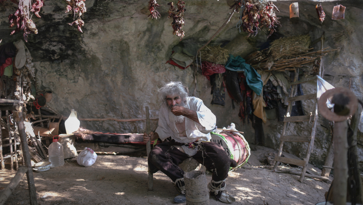 Serbian hermit Panta Petrovic eats in his cave in the southern Serbian city of Pirot, on August 9, 2021. - Almost twenty years ago, Panta Petrovic made social distancing a lifestyle choice when he moved into a tiny Serbian mountain cave to avoid society. Last year, on one of his visits to town, the dreadlocked man with a long beard found out there was a pandemic raging. After vaccines against Covid-19 became available, he got jabbed and urges everyone to do the same. (Photo by OLIVER BUNIC / AFP)