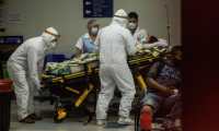 Paramédicos con equipo de protección para evitar el contagio de coronavirus ingresan a una mujer al área de emergencias del Hospital San Juan de Dios. Fotografía: Prensa Libre.