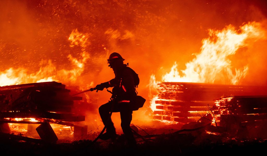 A firefighter douses flames as they push towards homes during the Creek fire in the Cascadel Woods area of unincorporated Madera County, California on September 7, 2020. - A firework at a gender reveal party triggered a wildfire in southern California that has destroyed 7,000 acres (2,800 hectares) and forced many residents to flee their homes, the fire department said Sunday. More than 500 firefighters and four helicopters were battling the El Dorado blaze east of San Bernardino, which started Saturday morning, California Department of Forestry and Fire Protection (Cal Fire) said. (Photo by JOSH EDELSON / AFP)