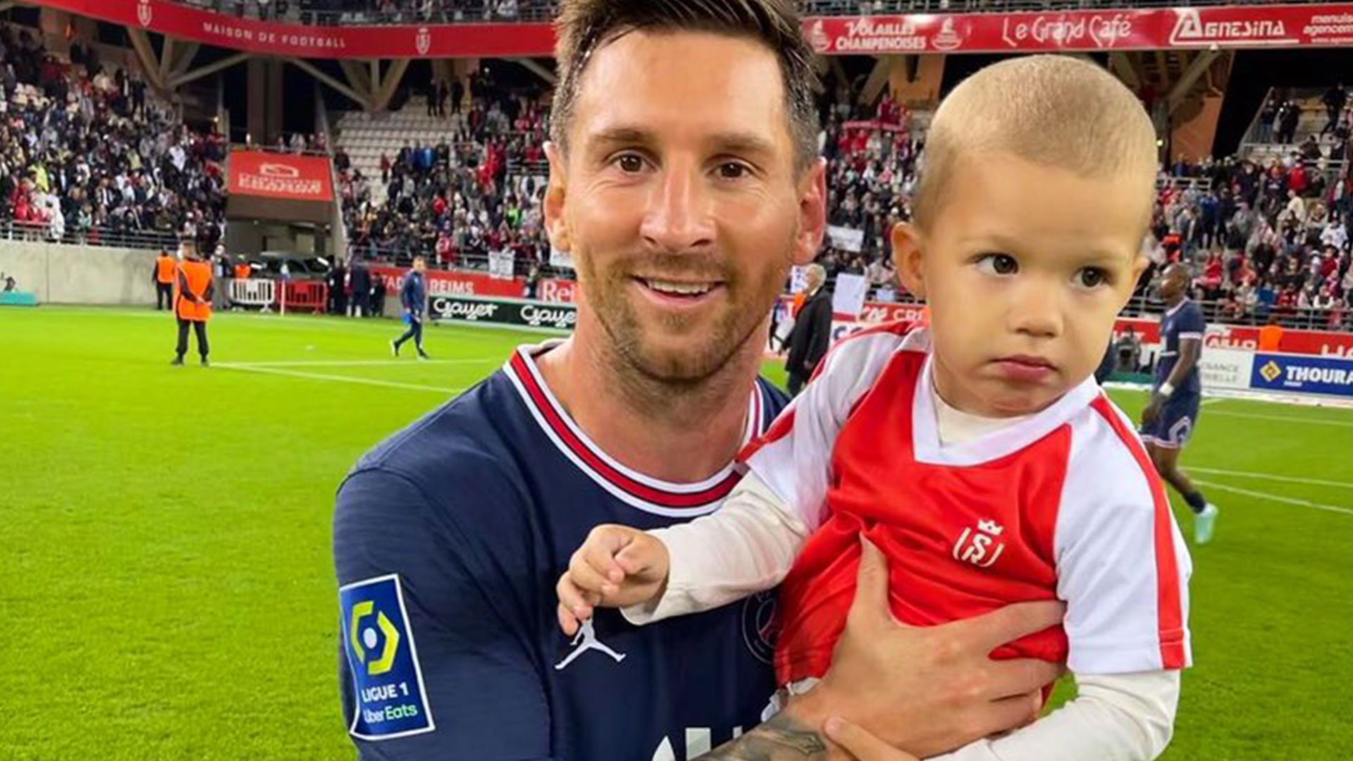 Lionel Messi sostiene en brazos al hijo del portero del Reims Predrag Rajkovic después de debutar en la victoria del PSG ante los rojiblancos. (Foto Prensa Libre: Movistar Deportes Twitter)
