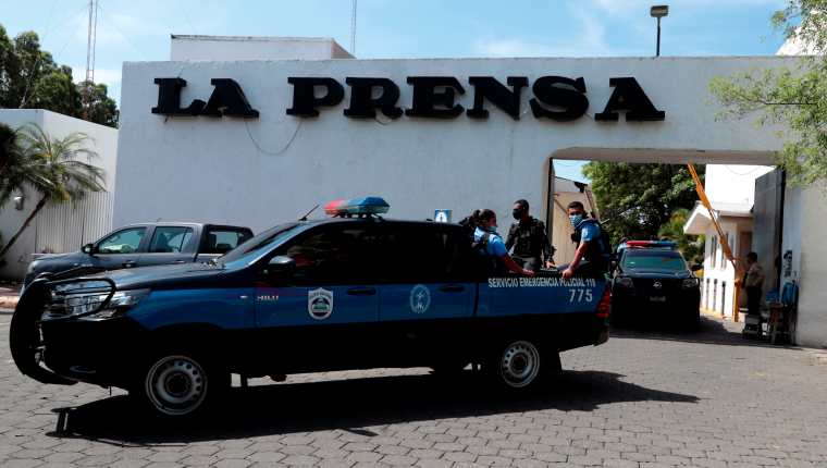 Miembros de la policía permanecen en la entrada de una propiedad de la Editorial "La Prensa" durante un operativo de allanamiento. (Foto Prensa Libre: EFE)