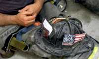 New York (United States), 13/09/2001.- A fireman rests his helmet with the American flag in his lap during a break from the search and rescue mission at the World Trade Center in New York, USA, 13 September 2001 (reissued 03 September 2021). On 11 September 2001, during a series of coordinated terror attacks using hijacked airplanes, two airplanes were flown into the World Trade Center's twin towers causing the collapse of both towers. A third plane targeted the Pentagon and a fourth plane heading towards Washington, DC ultimately crashed into a field. The 20th anniversary of the worst terrorist attack on US soil will be observed on 11 September 2021. (Atentado, Terrorista, Incendio, Estados Unidos, Nueva York) EFE/EPA/BETH A. KEISER / POOL *** Local Caption *** 53010317