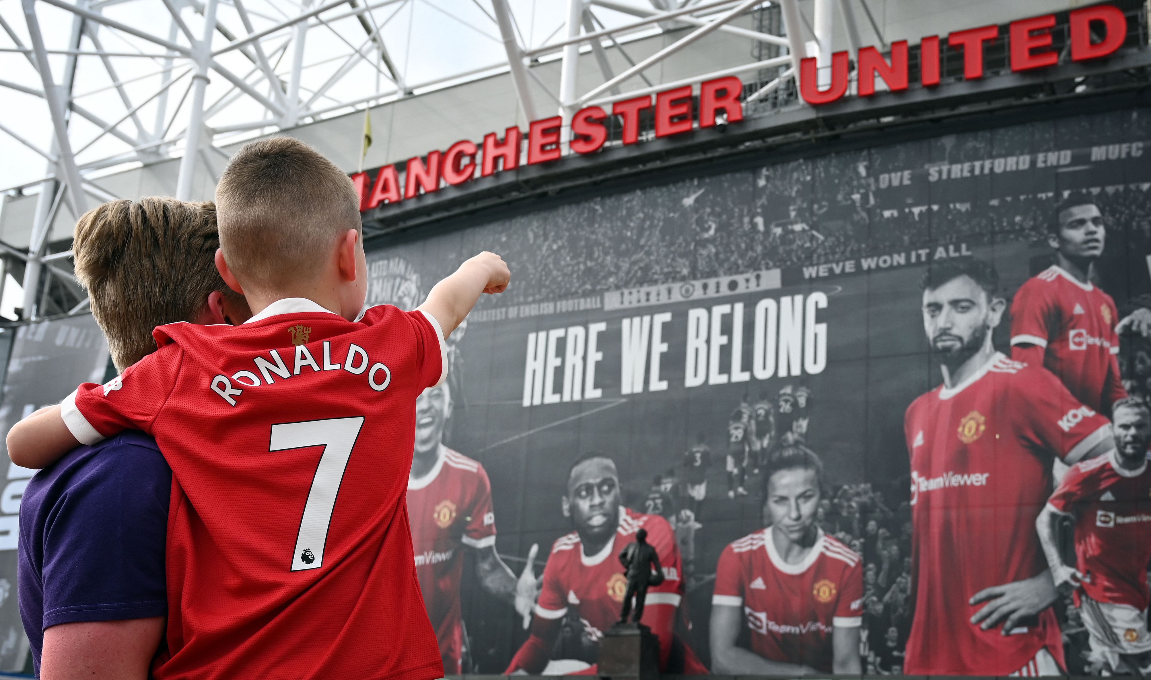 Un pequeño aficionado viste la camisola del Manchester United con el nombre y número de Cristiano Ronaldo. Señala  hacia el estadio de Old Trafford donde podría debutar este 11 de septiembre. Foto Prensa Libre: AFP.