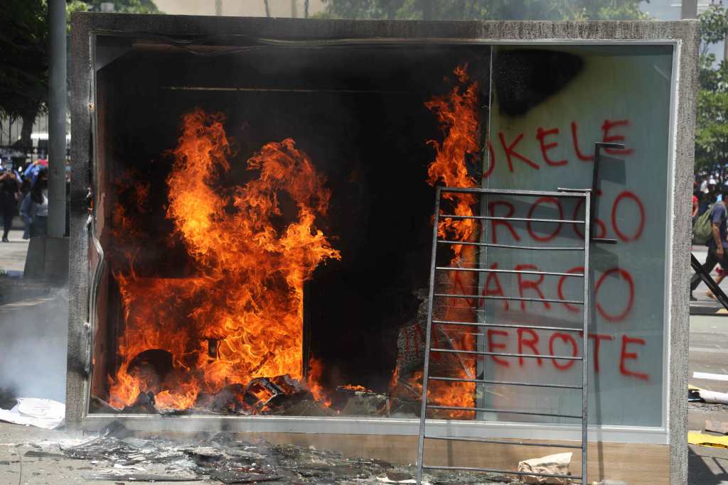 Manifestantes incendian uno de los llamados "chivos", utilizados para hacer transacciones con bitcóins en El Salvador. (Foto Prensa Libre: AFP)
