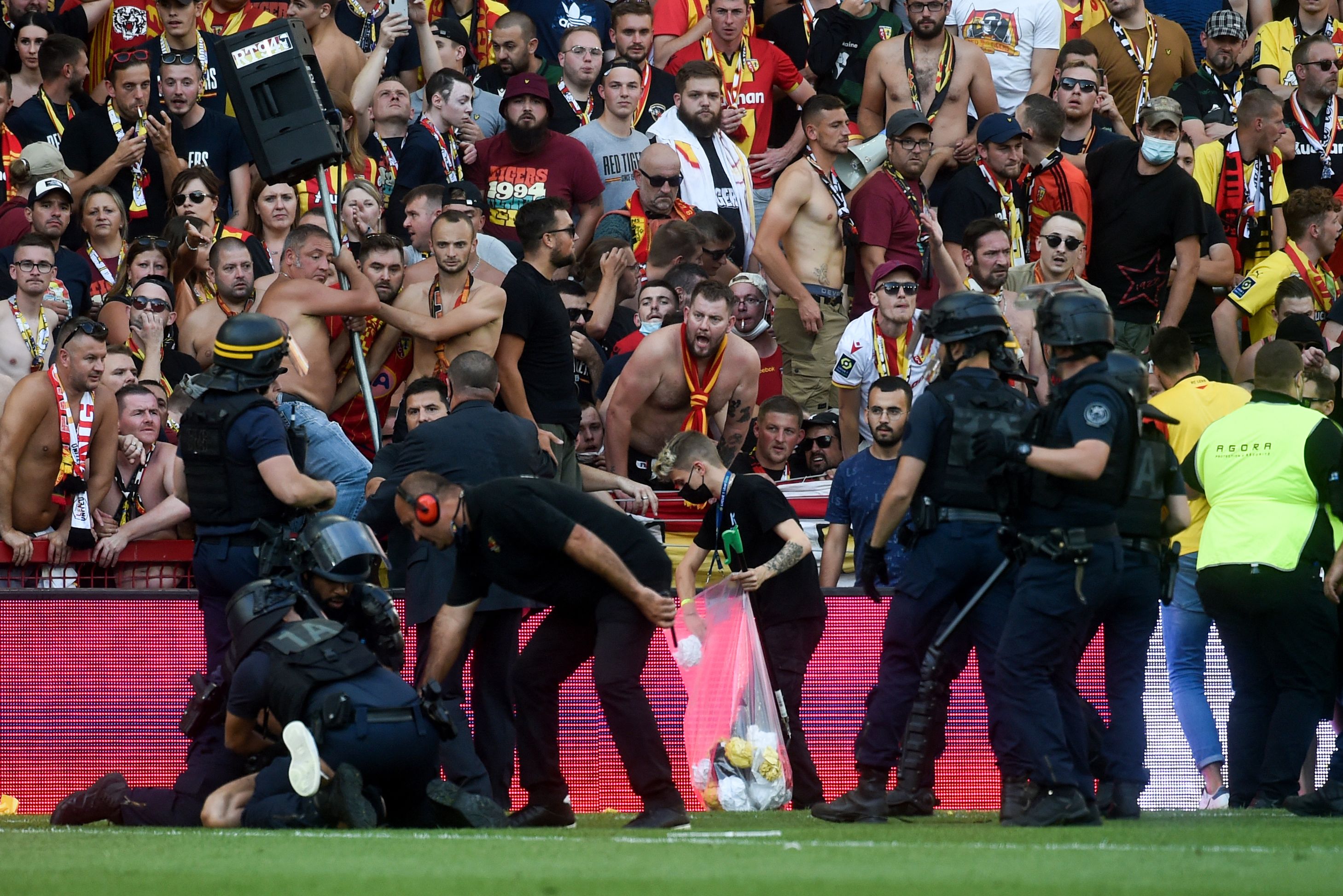 La policía arresta a un hombre luego de que los fans del Lens invadieran la cancha  del Stade Bollaert-Delelis. (Foto Prensa Libre: AFP)