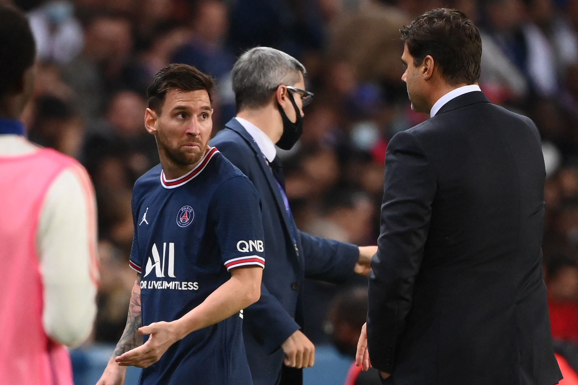El jugador del Paris Saint-Germain Lionel Messi (izq) deja el campo mientras habla con Mauricio Pochettino en el partido ante el  Olympique Lyonnais en el Parc des Princes. (Foto Prensa Libre: AFP)