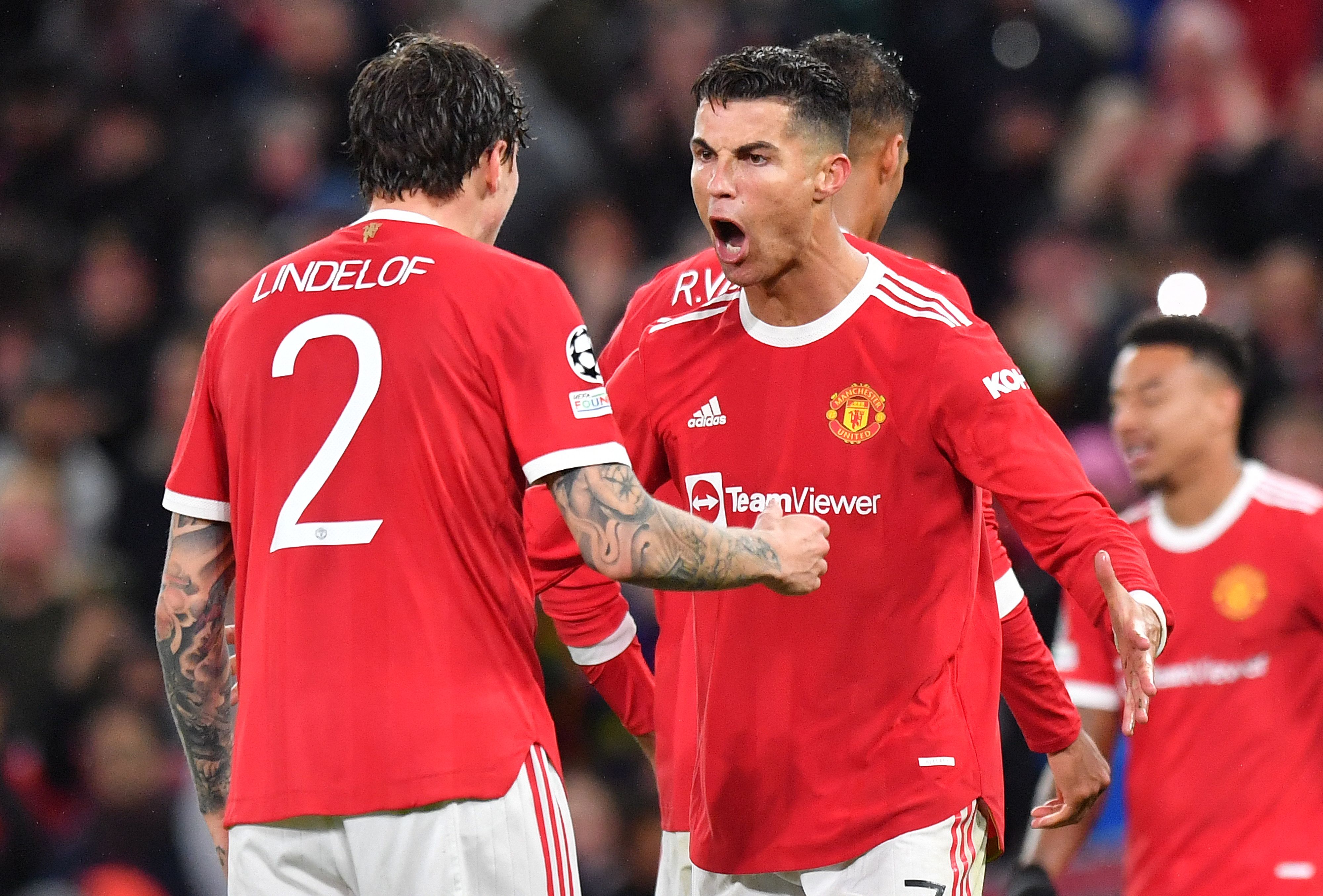 Manchester United's Portuguese striker Cristiano Ronaldo (C) celebrates with Manchester United's Swedish defender Victor Lindelof at the final whistle in the UEFA Champions league group F football match between Manchester United and Villarreal at Old Trafford stadium in Manchester, north west England, on September 29, 2021. - Manchester United won the match 2-0. (Photo by Anthony Devlin / AFP)