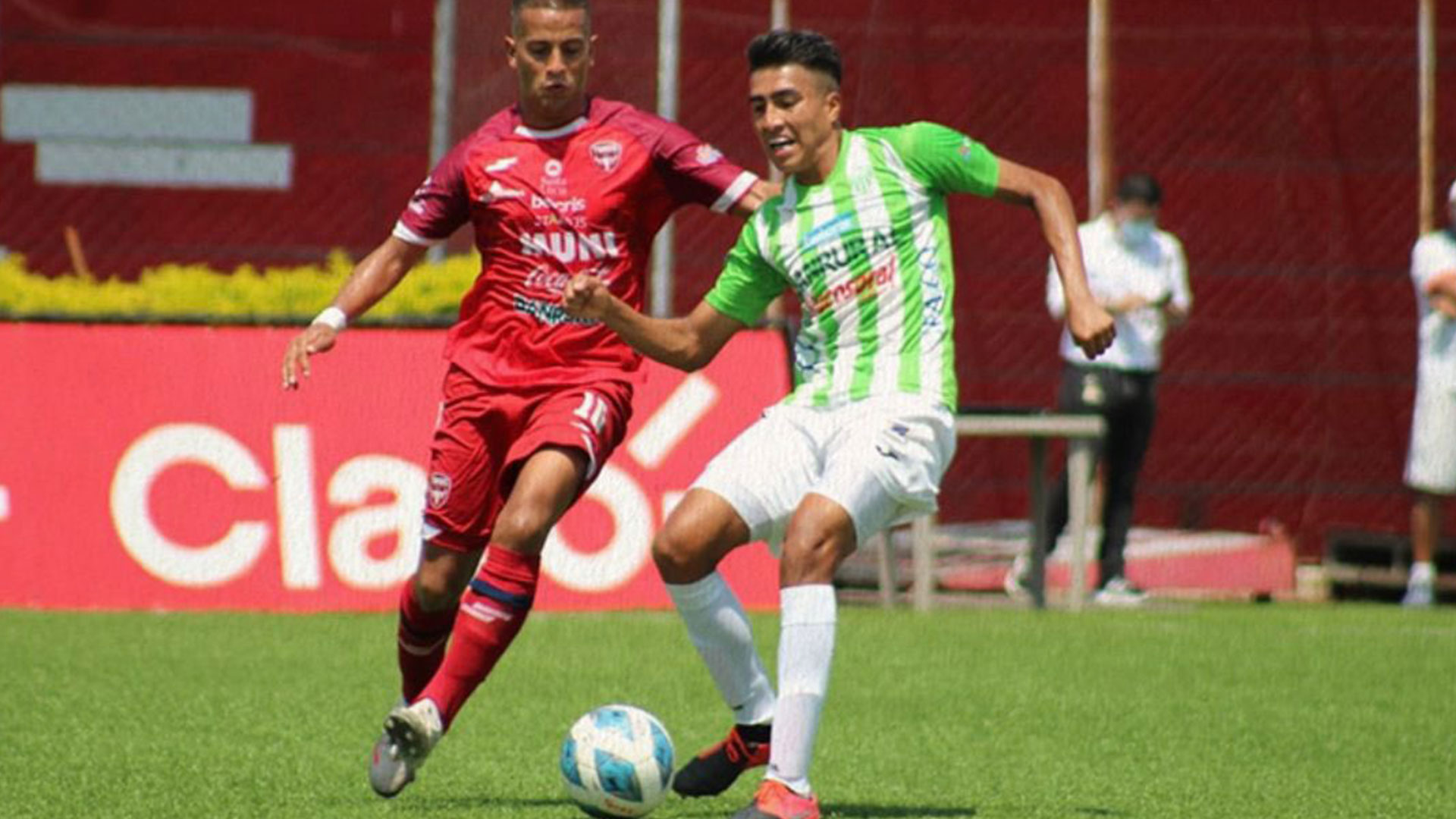 El jugador de Malacateco Kenneth Cerdas (rojo) disputa el balón a un futbolista de Antigua en el duelo realizado el domingo sobre la cancha del Estadio Municipal Santa Lucía. (Foto Prensa Libre: Antigua GFC Twitter)