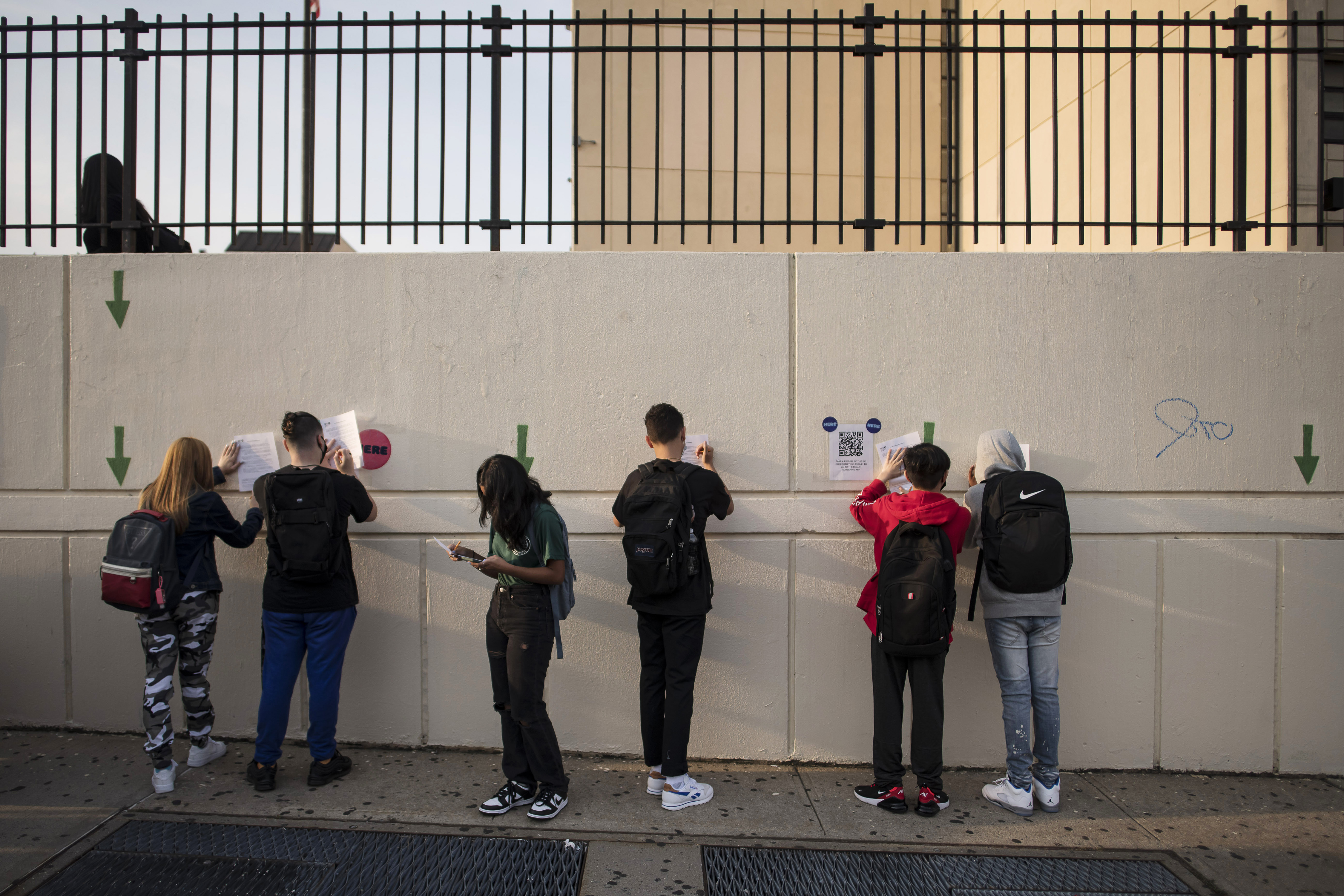 estudiantes rellenan formularios de examen de salud en papel mientras llegan a la escuela secundaria Herbert H. Lehman en el Bronx el lunes 13 de septiembre de 2021.  (Foto Prensa Libre: Karsten Moran/The New York Times)