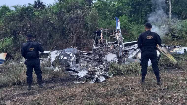 Agentes de la PNC resguardan los restos de una avioneta quemada, en San Luis, Petén, para que peritos del MP recaben evidencias. (Foto Prensa Libre: PNC)