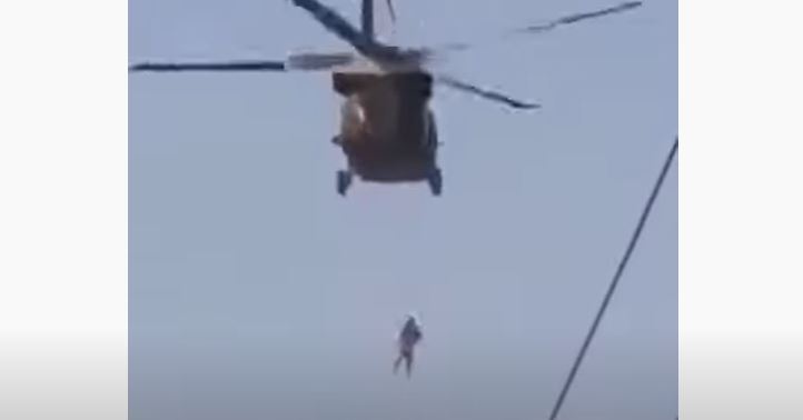 Momento en que helicóptero se desplaza con una persona colgando en Afganistán. (Foto Prensa Libre: Tomada de video de YouTube)