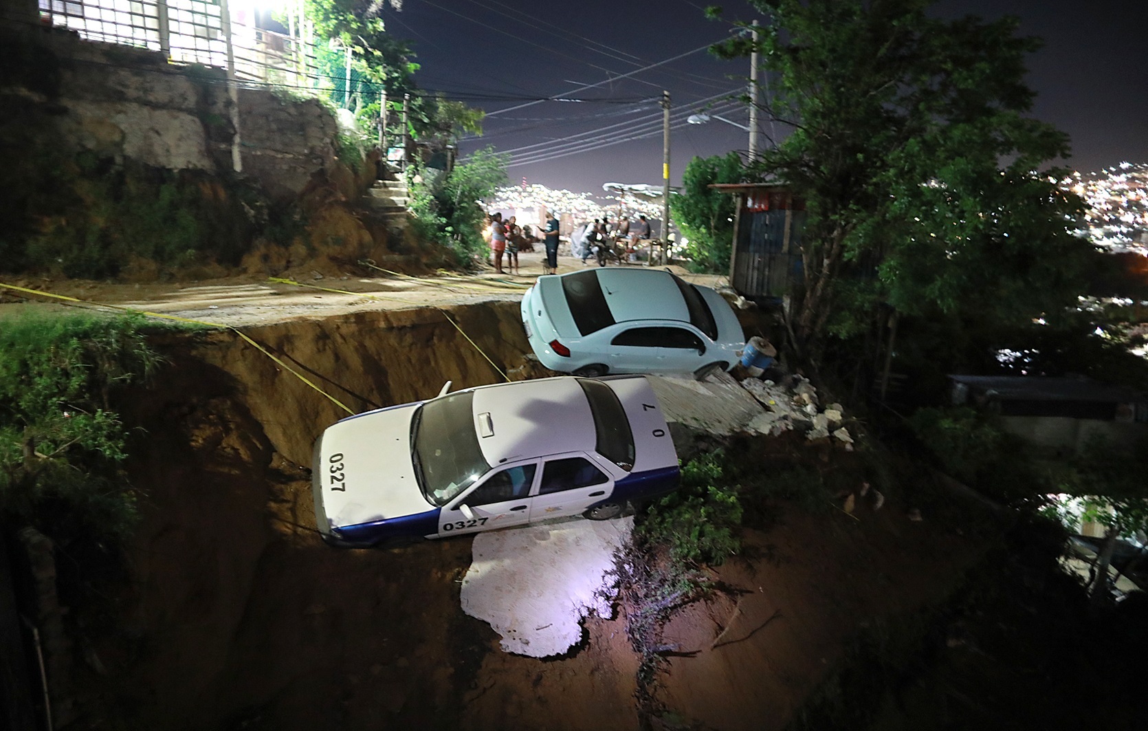 Dos vehículos quedaron a punto de caer a un barranco por el suelo reblandecido, debido al sismo de 7.1, en el balneario de Acapulco, Guerrero.  (Foto Prensa Libre: EFE)