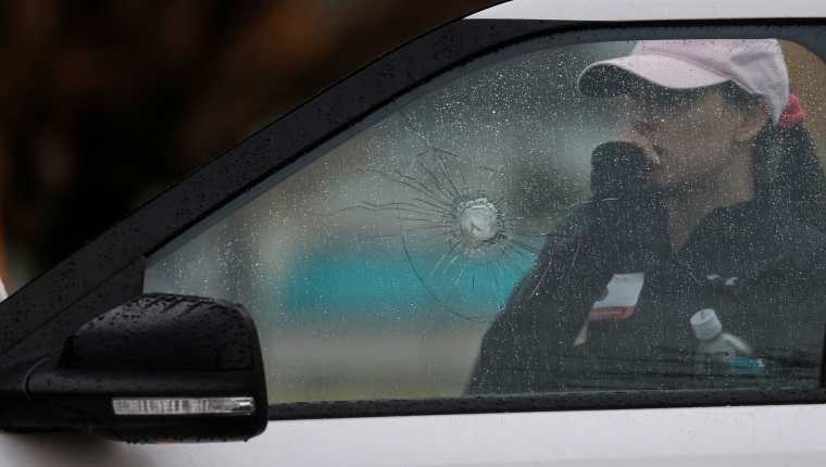 A woman stands behind a car with shattered glass near the scene of a shooting at the Boise Towne Square shopping mall in Boise, Idaho, U.S., October 25, 2021. REUTERS/Shannon Stapleton