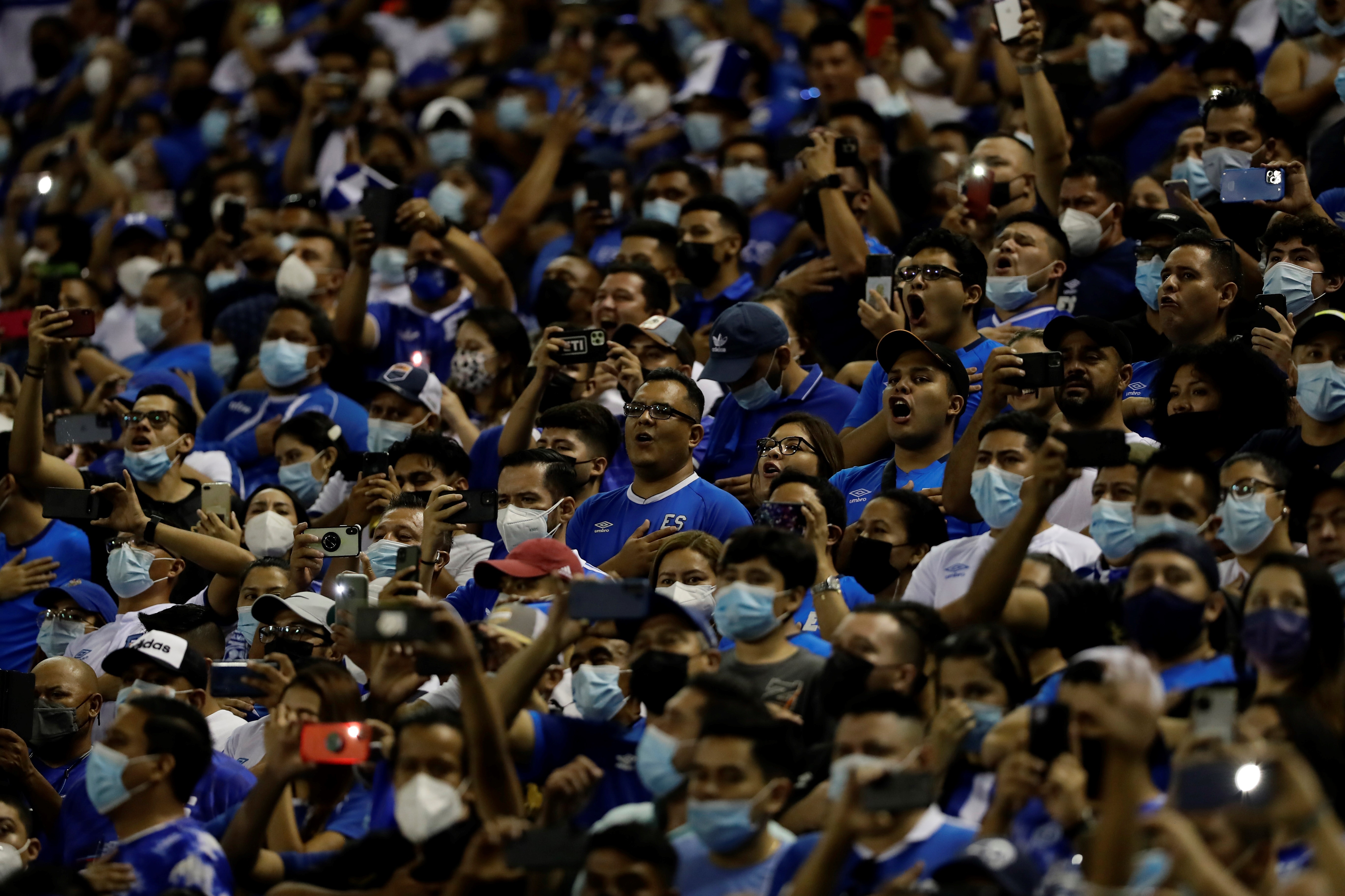 Aficionados salvadoreños cantan el himno nacional durante el juego entre El Salvador y México, en su juego de octogonal por las eliminatorias al mundial Catar 2022, hoy en el Estadio Cuscatlán en San Salvador. (Foto Prensa Libre: EFE)