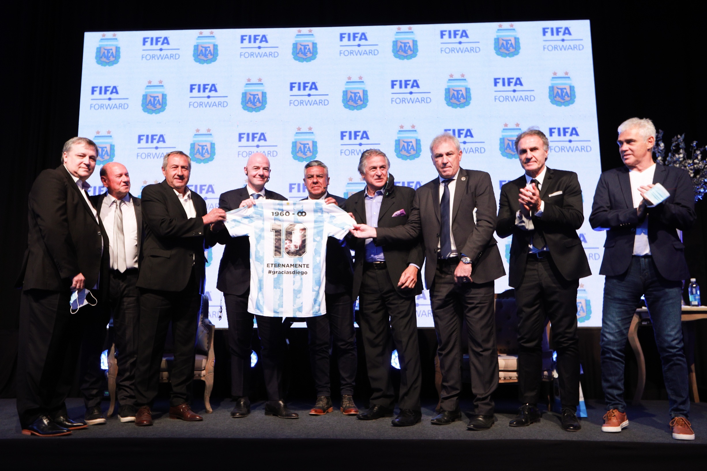 Fotografía cedida por la Asociación del Fútbol Argentino (AFA) de su presidente Claudio Tapia (5-i) posando sosteniendo una camiseta de la selección argentina dedicada al fallecido Diego Maradona con el presidente de la FIFA, Gianni Infantino (4-i),acompañados por jugadores excampeones del mundo en una rueda de prensa en Buenos Aires (Argentina). Foto Prensa Libre: EFE.