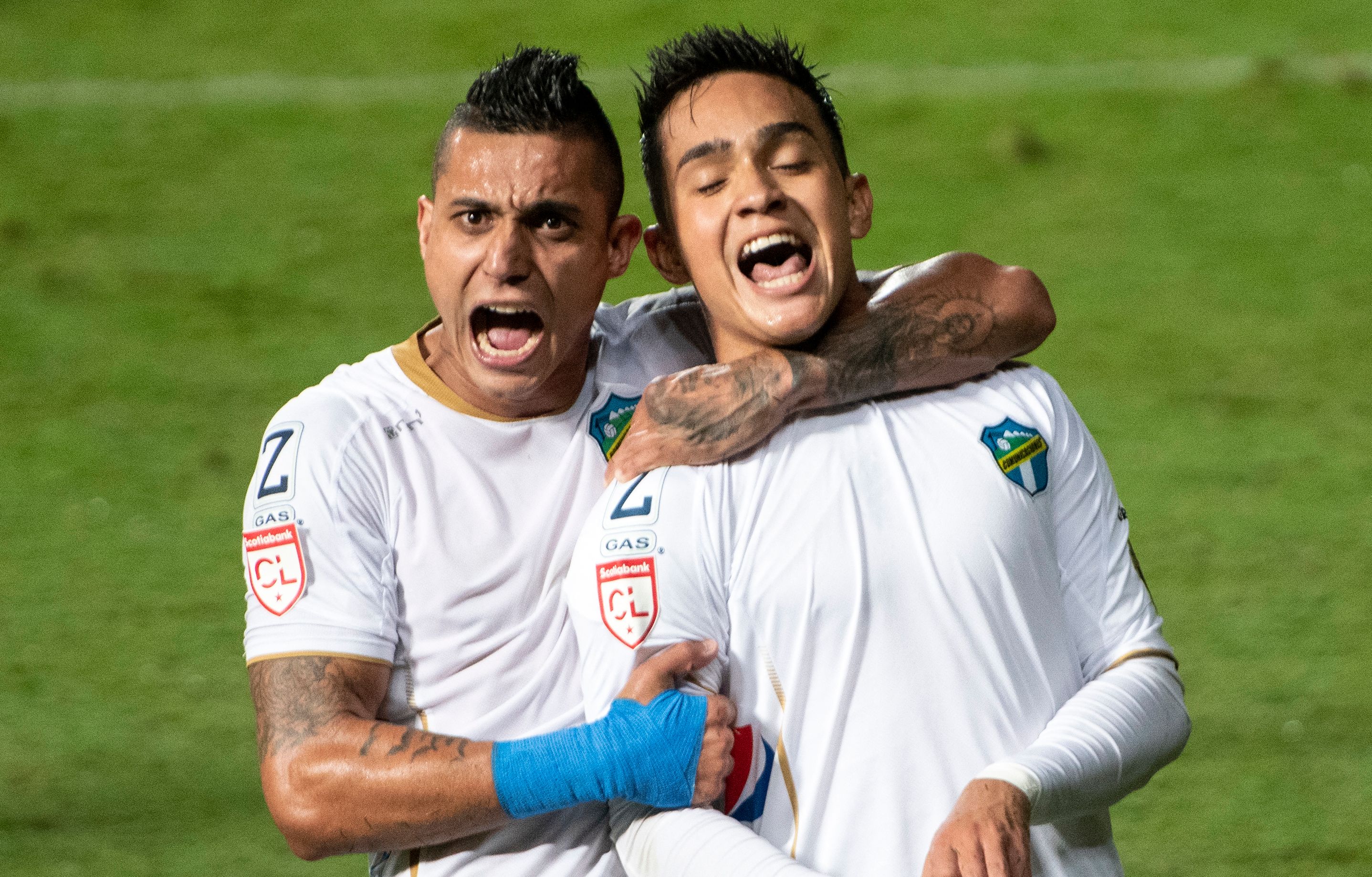 Guatemala's Comunicaciones Oscar Santis (R) celebrates with Jorge Aparicio after scoring against Costa Rica's Saprissa during their Concacaf Champions league quarter-final first leg football match at the Ricardo Saprissa Stadium in San Jose, on October 21, 2021. (Photo by Ezequiel BECERRA / AFP)