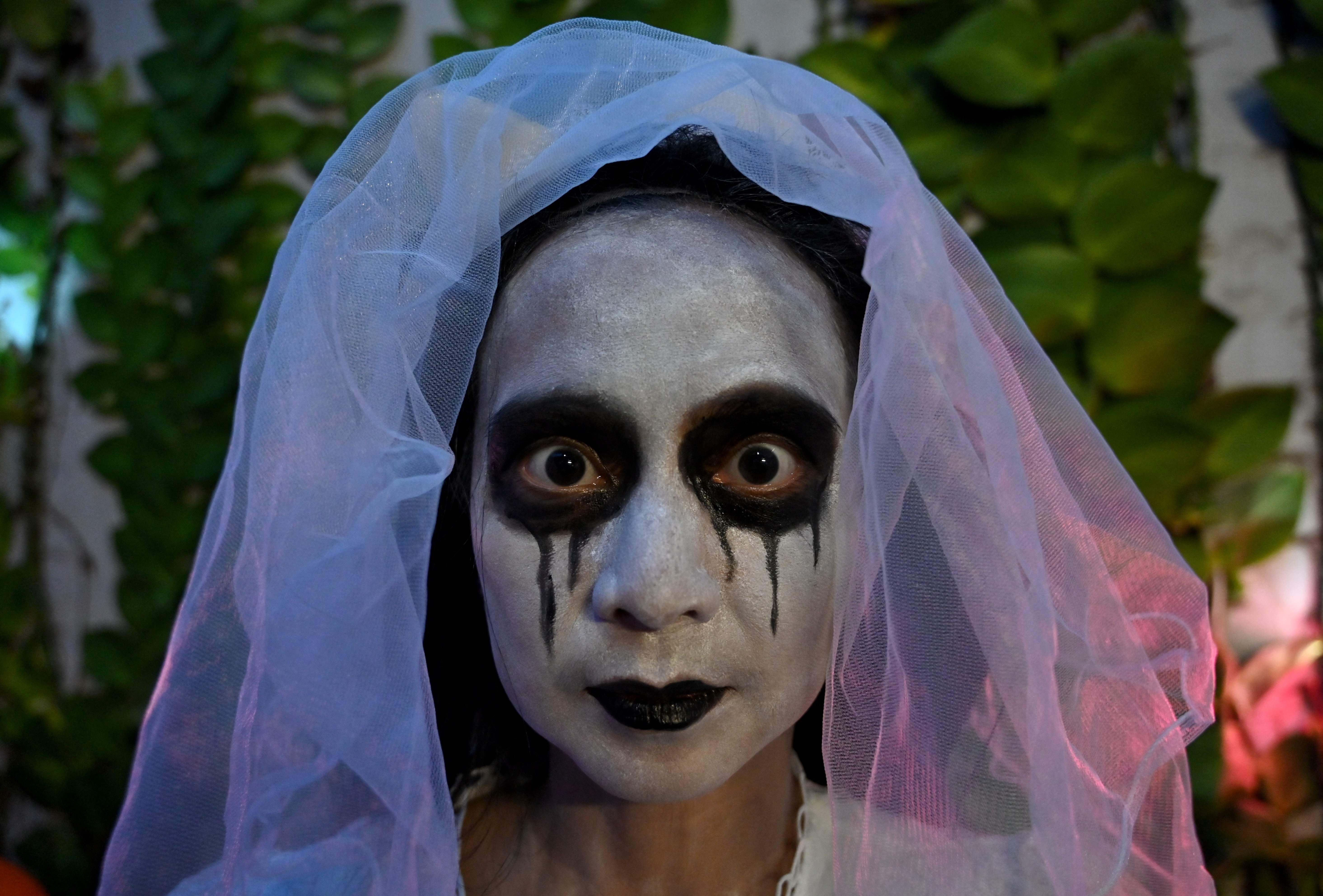 A woman gets her face painted during a Halloween party at a café in Tangerang on October 31, 2021. (Photo by ADEK BERRY / AFP)