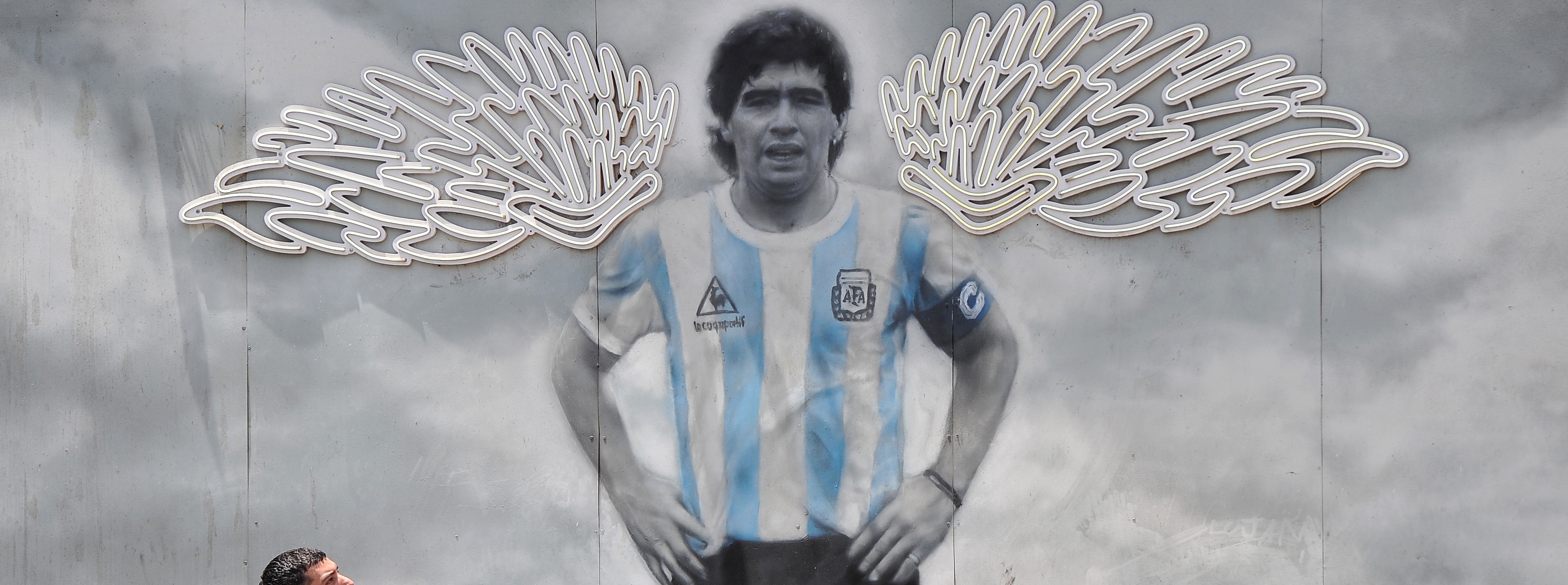 Un hombre camina frente a un mural con la imagen del astro del fútbol Diego Maradona en el barrio Chacarita, Buenos Aires. (Foto Prensa Libre: EFE)