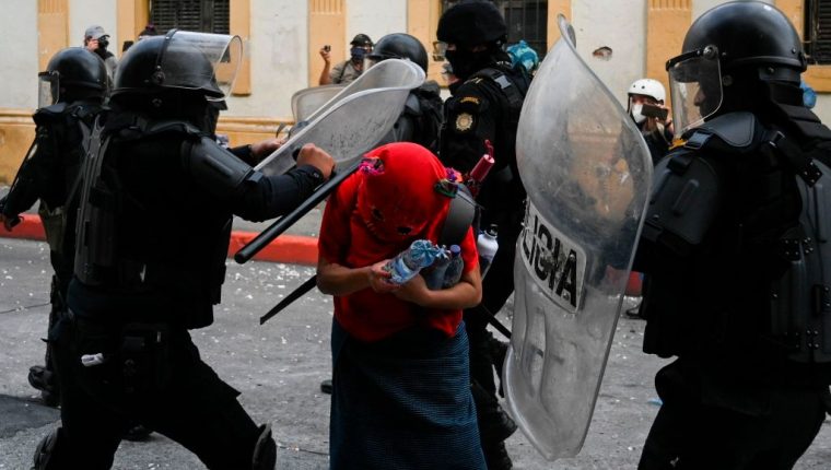 Riot police attack a demosntrator during a protest demanding the resignation of Guatemalan President Alejandro Giammattei, in Guatemala City on November 21, 2020. - The Vice President of Guatemala, Guillermo Castillo, asked President Alejandro Giammattei to resign together for 