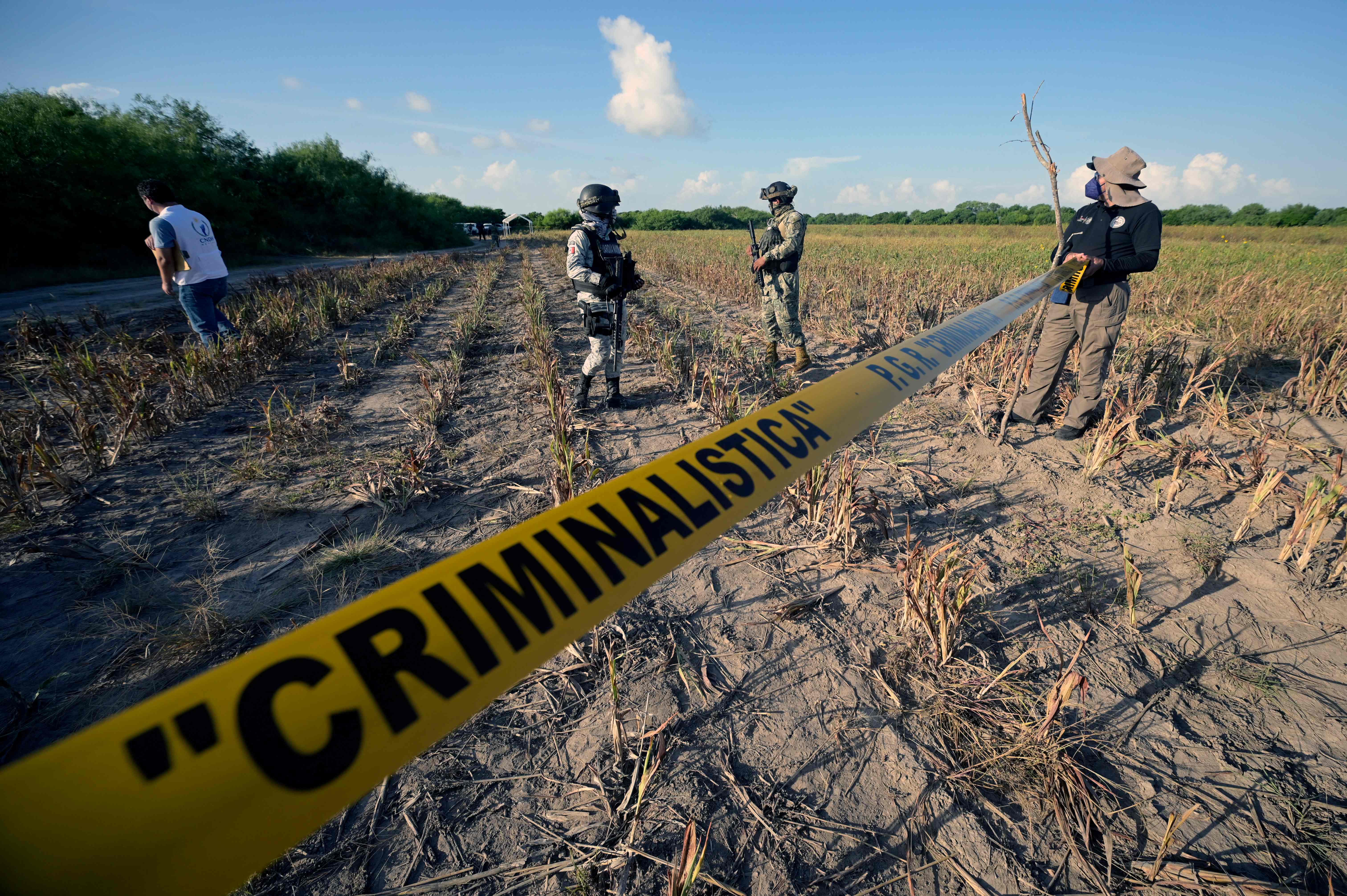 An agent of the Attorney General's Office, a member of the National Guard and member of the Mexican Navy guard the entrance to a property called 