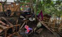 A woman reads at her yard in the Moravia neighborhood as local authorities try to implement an eviction order to evacuate families living in alleged illegal constructions, in Medellin, Colombia, on November 3, 2021. - The Moravia neighborhood is known for having been built on a garbage dump and for being from where late drug lord Pablo Escobar set up his first political campaign, and where he helped to build a football field and to install the electric network. (Photo by JOAQUIN SARMIENTO / AFP)