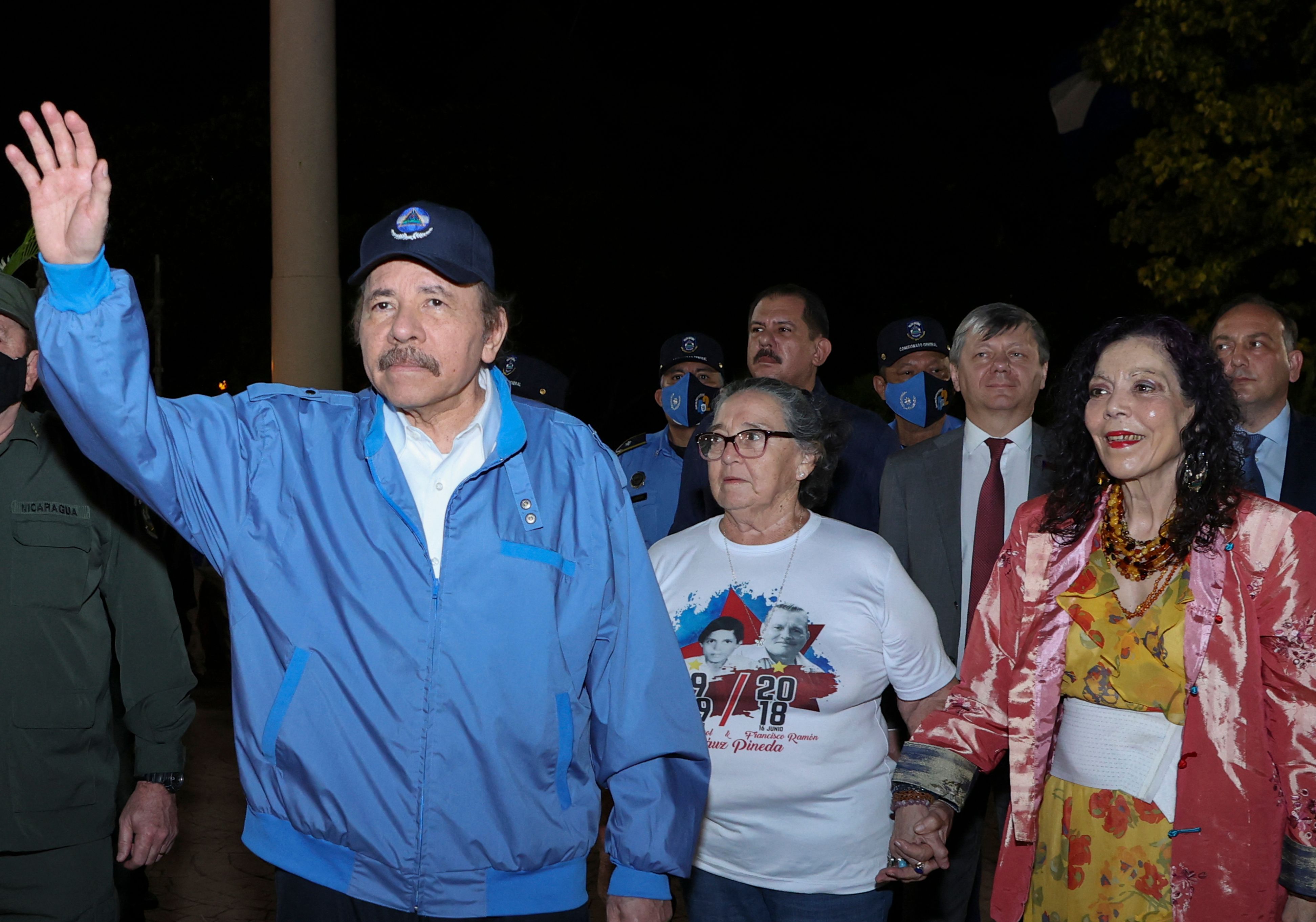 Handout picture released by the Nicaraguan presidency showing Nicaragua's President Daniel Ortega (L) waving at supporters during the commemoration of the 45th anniversary of the death of one of the founders of the Sandinista National Liberation Front (FSLN) guerrilla, Carlos Fonseca, in Managua, on November 8, 2021, as his wife and Vice-president Rosario Murillo (R) holds the hand of Amada Pineda, mother of FSLN activist Francisco Arauz Pineda who died during the 2018 unrest. - Nicaragua's longtime leader Daniel Ortega faced a torrent of international criticism after he won a fourth straight presidential term on November 7, 2021 in what critics described as a 