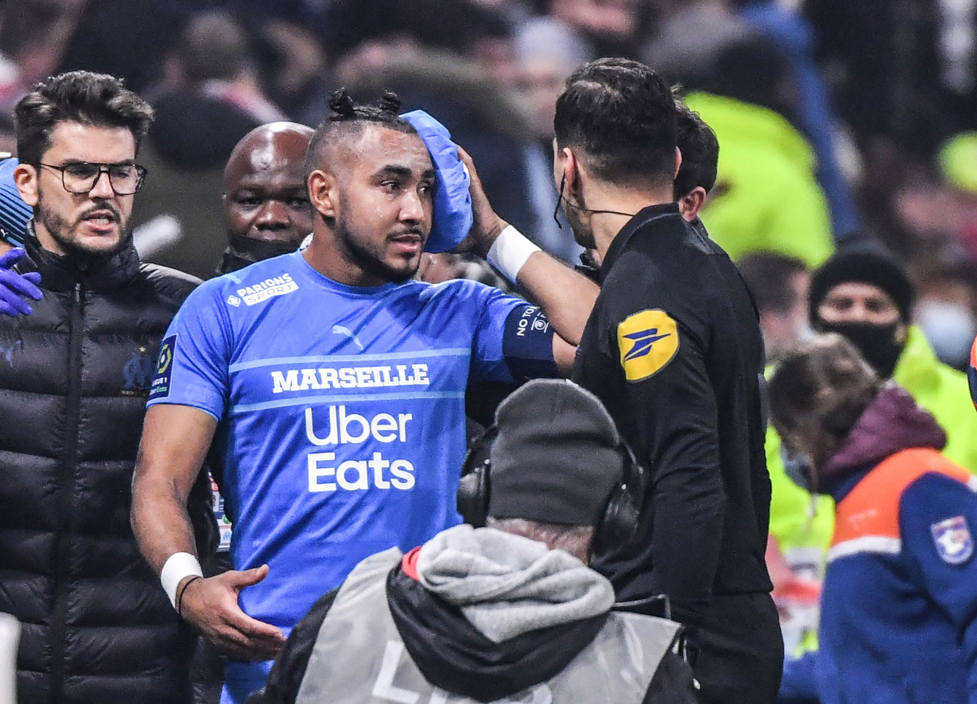 El jugador del Marsella Dimitri Payet (c) abandona el campo después de recibir botellazo en la cabeza en el Groupama. (Foto Prensa Libre: AFP)