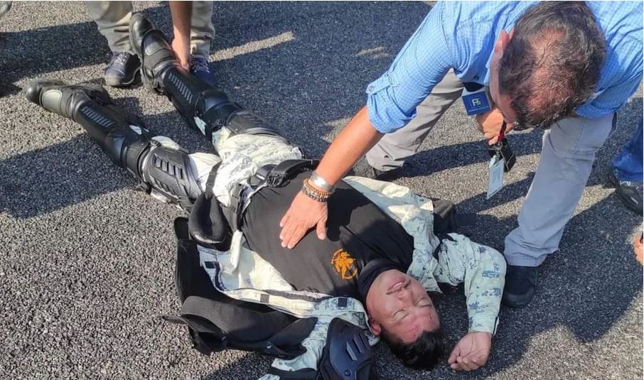 Un periodista le presta ayuda a un elemento de la Guardia Nacional que quedo inconsciente luego de ser vapuleado por los migrantes. (Foto Prensa Libre: Gabriela Coutiño)