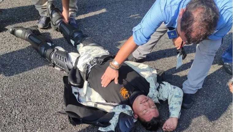 Un periodista le presta ayuda a un elemento de la Guardia Nacional que quedo inconsciente luego de ser vapuleado por los migrantes. (Foto Prensa Libre: Gabriela Coutiño)