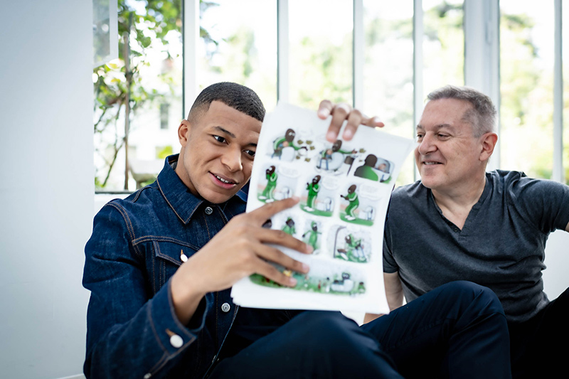 El jugador del Paris Saint-Germain Kylian Mbappé junto al artista del cómic Faro que le presenó su obra. (Foto Prensa Libre: kylianmbappe.com)