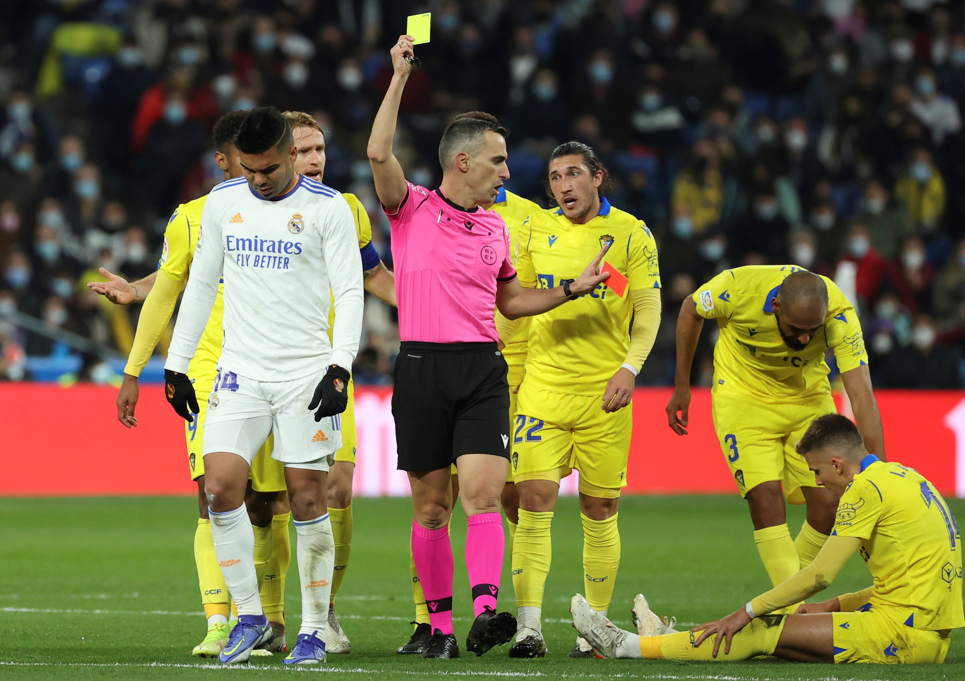 El colegiado Jaime Latre muestra tarjeta amarilla al centrocampista brasileño del Real Madrid, Carlos Henrique Casemiro (i), tras realizar una entrada sobre el delantero del Cádiz, Iván Alejo. (Foto Prensa Libre: EFE)