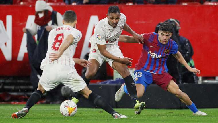El defensa brasileño del Sevilla FC Fernando Reges (C) pelea un balón con Abdessamad Ezzalzouli, del FC Barcelona. (Foto Prensa Libre: EFE)
