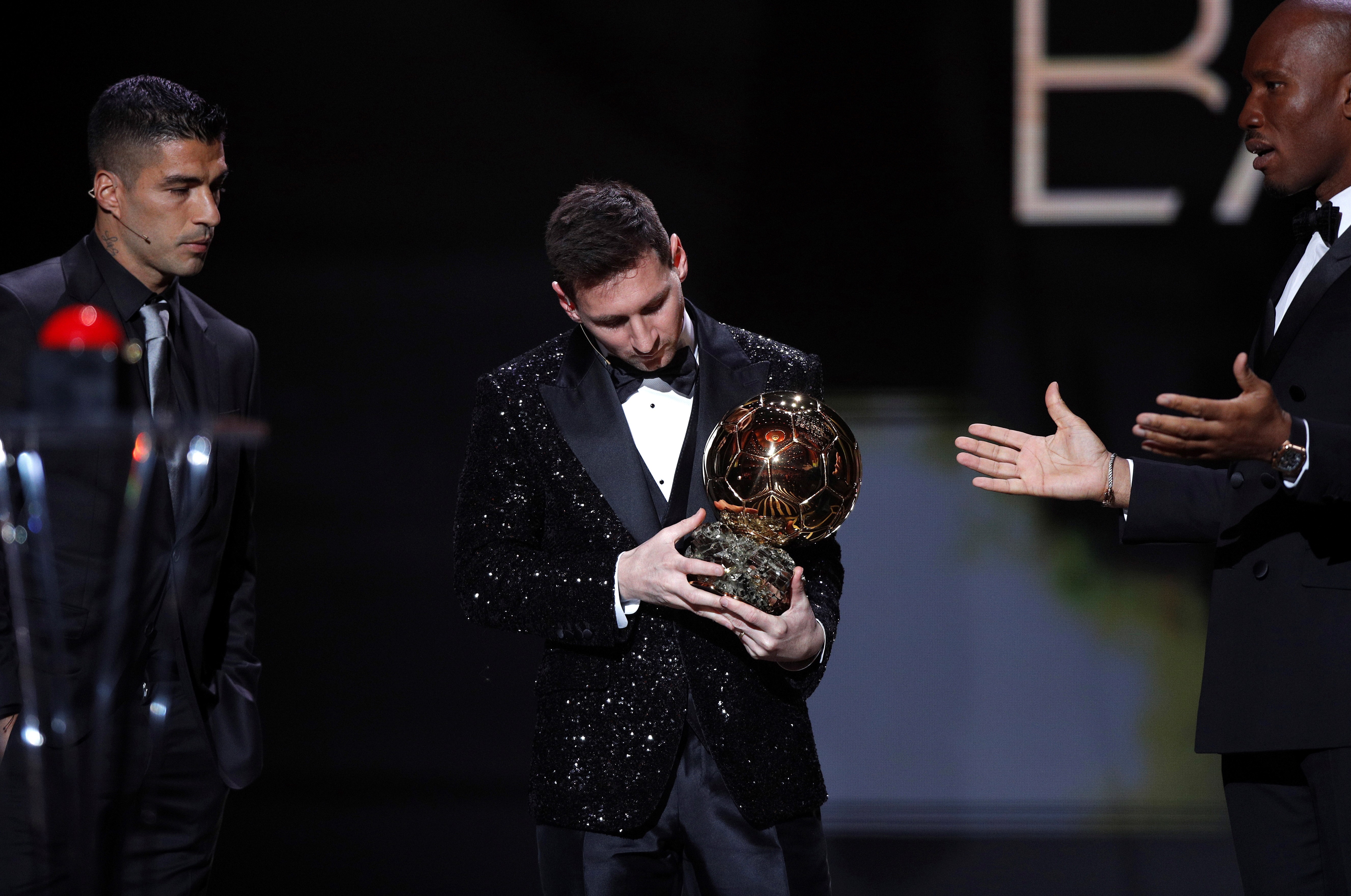 El delantero argentino del PSG Lionel Messi, flanqueado por su ex compañero Luis Suárez (i) y por el presentador de la gala Didier Drogba, recibe el Balón de Oro el 29 de noviembre de 2021, en el Teatro du Chatelet de París. Foto Prensa Libre: EFE.