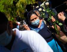 Una mujer sostiene flores blancas durante la conmemoración del 40 aniversario de una masacre en El Mozote, a 200 km al este de San Salvador, el 11 de diciembre de 2021. (Foto: AFP)