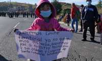 A child holds a sign reading We want land demarcation. We don´t want any more shots. We want peace in our municipalities and villages as people   block a road during a ceremony in homage of people killed in the village of Chiquix, in Santa Catarina Ixtahuacan, Guatemala, on December 20, 2021. - At least 13 people were killed in western Guatemala, including women, children and a policeman, in a long-running land dispute between indigenous villages, police said Saturday. (Photo by Johan ORDONEZ / AFP)