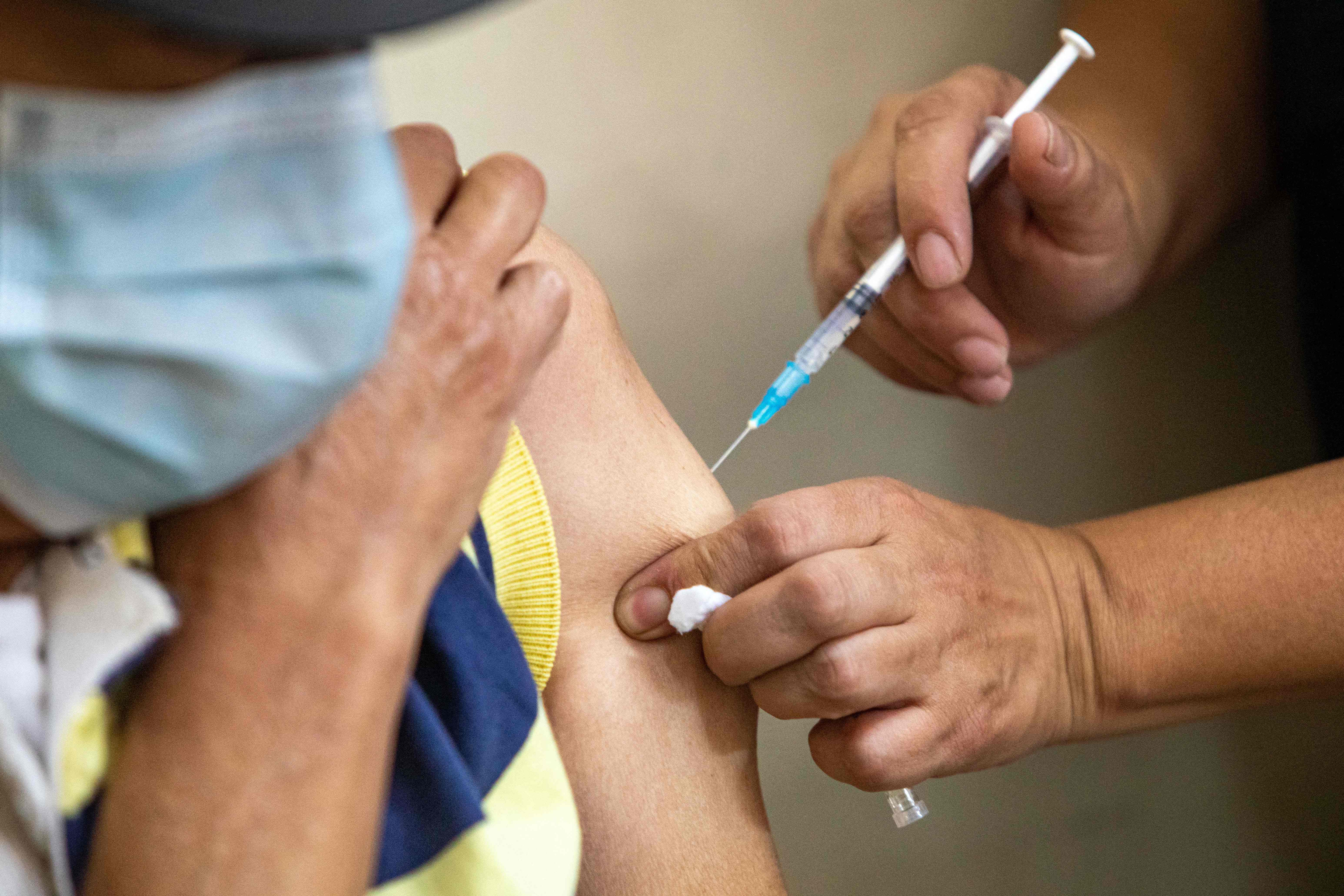 A woman is vaccinated against COVID-19 at the Health Center No. 1 of the Ministry of Public Health, in the Historic Center in Quito, on December 24, 2021. - Ecuador, on the eve, became the first country to make coronavirus vaccines obligatory for children as young as five, following the arrival of the Omicron variant in the South American country. (Photo by Cristina Vega RHOR / AFP)