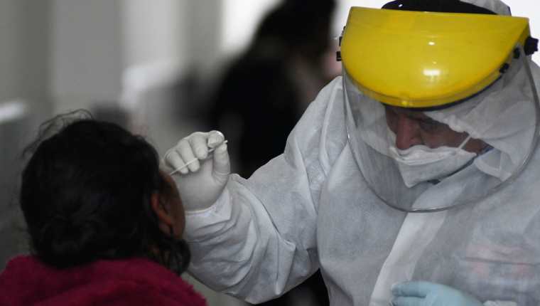 Una trabajadora de salud hace un hisopado en un centro de atención de la capital. Los casos de covid-19 comienzan a repuntar en medio del temor de que ómicron ya está presente en el país. (Foto Prensa Libre: AFP)
