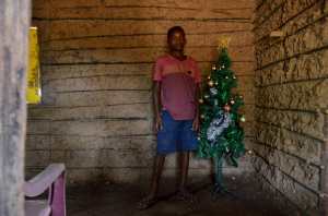 Gabriel Silva poses with a christmas tree inside his house in Pinheiros, Maranhao state, Brazil, on December 10, 2021. - An illegal garbage dump seems an unlikely setting for a holiday story, but when a photojournalist captured 12-year-old Gabriel Silva pulling a Christmas tree from a fetid mountain of trash, the image quickly went viral. (Photo by JOAO PAULO GUIMARAES / AFP)