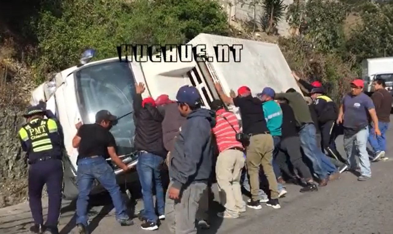Hombres levantan pesado camión que volcó y obstaculizada el pasó en una carretera de Huehuetenango. (Captura de video).